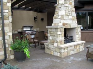 An outdoor kitchen complete with cozy fireplace.