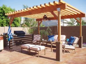 A beautiful concrete patio with BBQ island, modern patio furniture, and a natural-wood pergola.