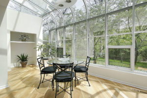 A beautiful sunroom with a table in the middle of the room.