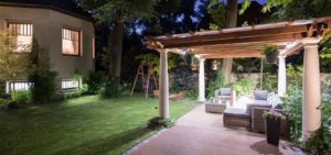 A backyard at night with a lit-up pergola