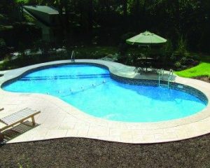 Custom shape inground pool with contrasting light and dark pool deck surface