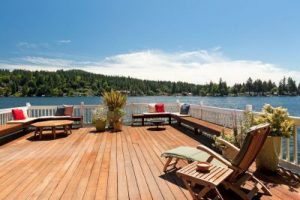 Wood deck overlooking water with benches and a lounge chair