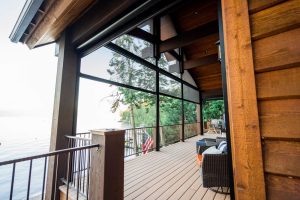 A screened-in porch facing a lake behind a cabin